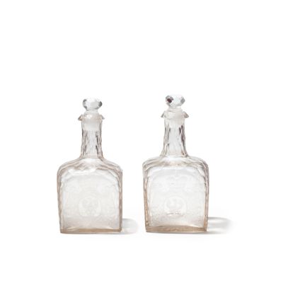 two clear glass bottles with silver tops sitting next to each other