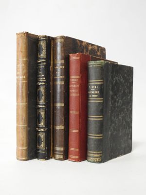 several old books are stacked on top of each other on a white surface