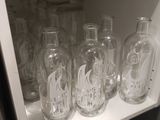 several empty glass bottles are lined up on a shelf in a kitchen