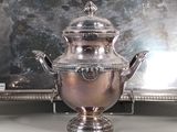 a silver tea pot sitting next to a silver tray on a table
