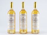 three bottles of white wine sitting next to each other on a white surface