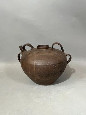 un vase marron muni d'anses, sur un fond blanc