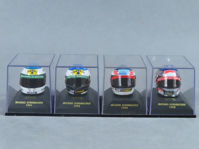 quatre casques de course miniatures dans une vitrine posée sur une surface grise