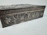 an antique silver box with a floral design on the lid