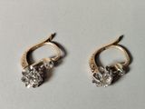 two pairs of gold and diamond earrings on a white surface
