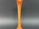 an orange vase sitting on top of a black table next to a gray wall
