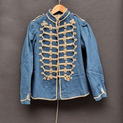 une vieille veste militaire bleue accrochée au mur à côté d'un cintre en bois