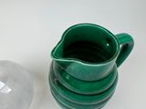 a green pitcher sitting next to a glass container