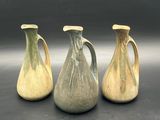 three vases are sitting on a table with a black background