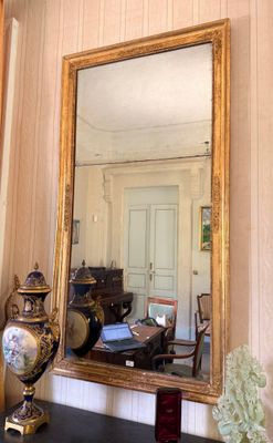 a mirror on the wall above a table with a vase