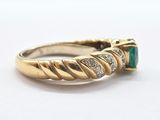 an image of a gold ring with a green stone surrounded by diamonds
