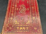 an old red book sitting on top of a black table