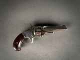 un gros plan d'un revolver posé sur une table, sur fond gris