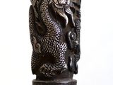 un dragon argenté sur une canne noire, sur fond blanc