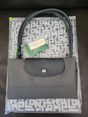 un sac à main gris muni d'une poignée noire et d'une étiquette verte