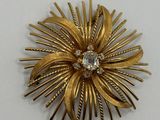 an image of a gold brooch with a diamond in the center