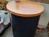 a black barrel with a wooden top sitting on the floor