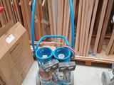 un chariot bleu sur lequel se trouvent deux bouteilles, à côté d'une caisse en bois