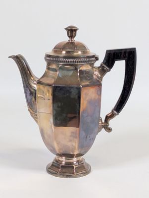 une théière ancienne en argent avec une poignée noire sur fond blanc