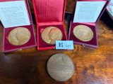 three gold medals sitting in a red case next to a coin