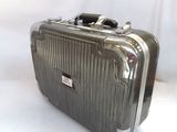une valise argentée posée sur une surface blanche