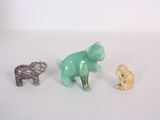 three small figurines of animals on a white surface