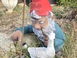 a statue of a gnome with a shovel in a garden
