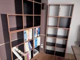 a room with a desk, bookshelf, and a television