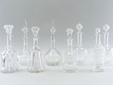 seven glass vases sitting next to each other on a table