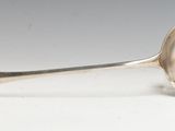 une cuillère en argent ancienne posée sur une table blanche