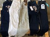 trois paires de jeans pour femmes suspendues à un portant devant un mur