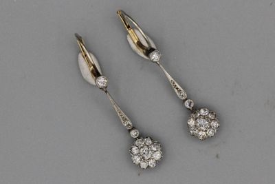 deux paires de boucles d'oreilles en diamant posées sur une surface grise