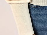 a close up of a person wearing a sweater and jeans