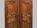 une vieille armoire en bois à deux portes, ornée de sculptures sur la façade