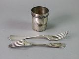 deux fourchettes et une tasse en argent posées sur une table