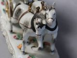 a figurine of a horse drawn carriage with people on it