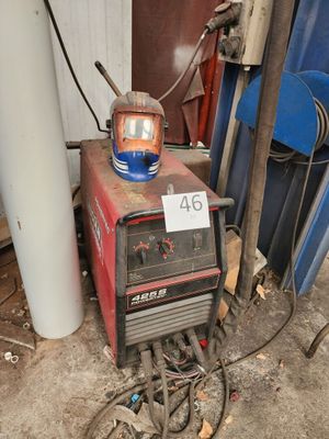 une soudeuse posée dans un garage, à côté d'un tas de vieilleries