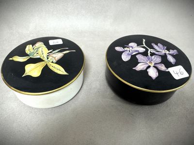deux boîtes noires et blanches ornées de fleurs, posées sur une table
