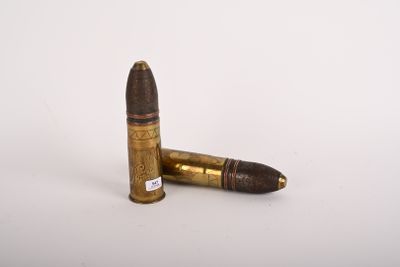 two bullet shells on a white surface with one bullet in the foreground
