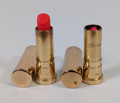 two red lipsticks sitting next to each other on a white surface