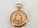 a close up of a gold pocket watch on a white surface