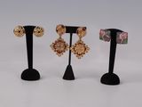 three pairs of earrings on stands with a white background
