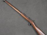 a rifle with a wooden barrel and a wooden handle on a gray surface