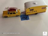 un camion miniature tirant une remorque sur laquelle est accrochée une pancarte