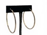 pair of gold hoop earrings on a black stand against a white background