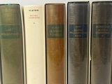 several books are lined up in a row on a white surface