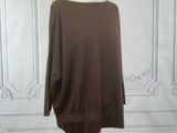 brown sweater on a mannequin stand in front of a white wall