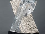 a sculpture of a rock and a piece of glass on top of a white pedestal