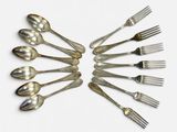 plusieurs fourchettes et cuillères disposées en cercle sur une surface blanche