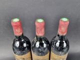 three bottles of red wine sitting on top of a table